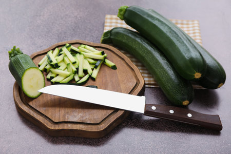 Fresh green zucchini and board with slices on purple backgroundの写真素材