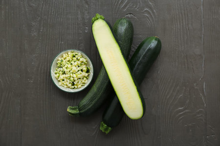 Fresh green zucchini and plate with slices on black wooden backgroundの写真素材