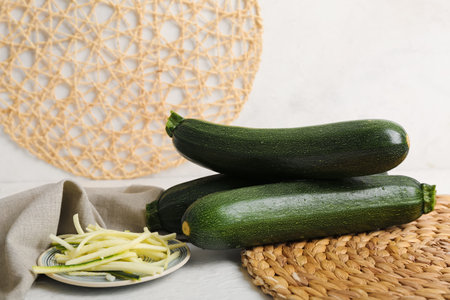 Fresh green zucchini and plate with slices on white backgroundの写真素材