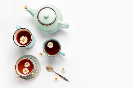 Teapot with cups of natural chamomile tea and flowers on white backgroundの写真素材