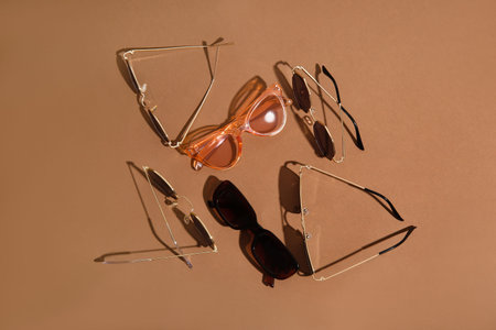 Different stylish sunglasses on brown background