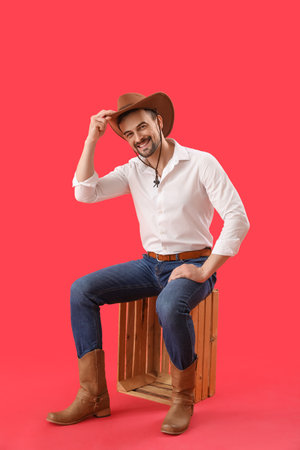 Handsome cowboy sitting on red backgroundの写真素材