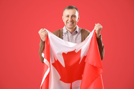 Mature man with flag of Canada on red backgroundの写真素材