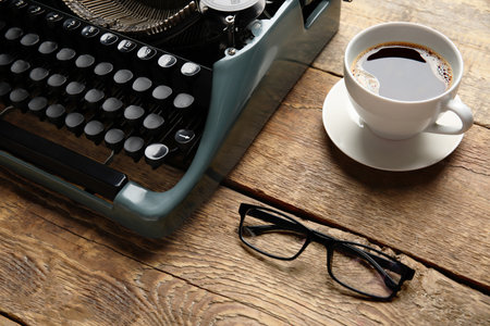 Vintage typewriter with cup of coffee and eyeglasses on brown wooden backgroundの写真素材