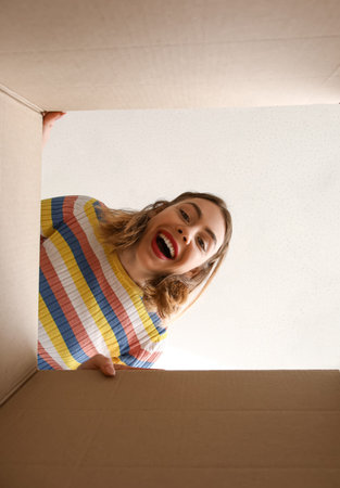 Young woman with open parcel at home, view from inside
