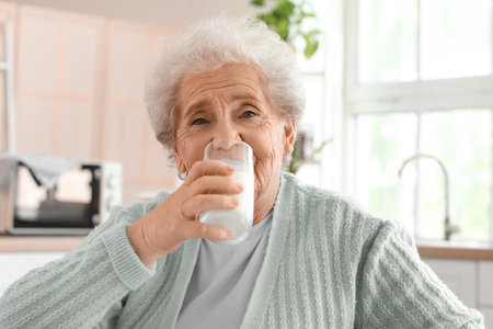 Senior woman drinking milk in kitchen, closeupの写真素材