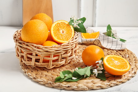 Basket of oranges with blooming branches on white tableの写真素材