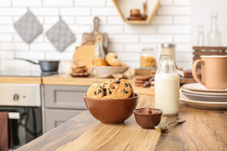 Bowl with cookies, bottle of milk and chocolate cream on wooden table in kitchenの写真素材