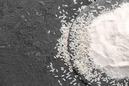 Plate with raw rice and flour on grunge black backgroundの写真素材