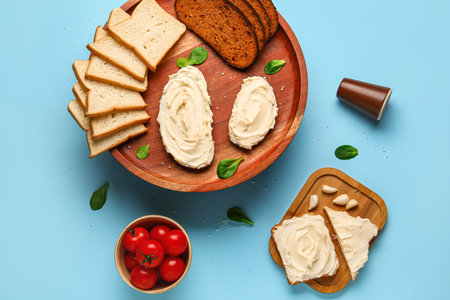 Tasty sandwiches and toasts with cream cheese on blue background