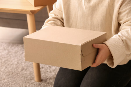 woman holding box with shoes in room