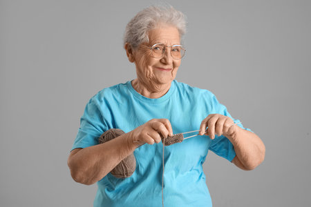 Senior woman knitting on gray backgroundの写真素材