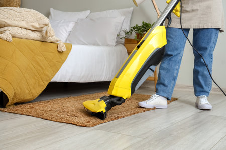 Housewife hoovering carpet in the bedroomの写真素材