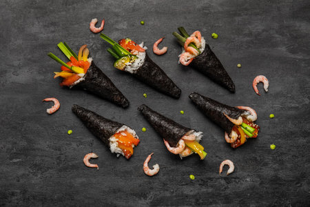 Composition with tasty sushi cones, shrimps and wasabi drops on dark backgroundの写真素材