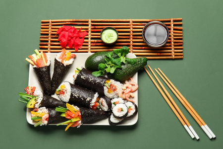 Plate with tasty sushi cones, rolls, wasabi, soy sauce and ginger on color backgroundの写真素材