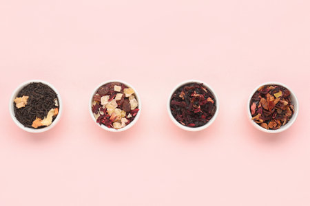 Bowls with different dried fruit tea on pink backgroundの写真素材