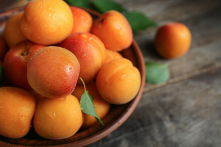Bowl with fresh apricots on wooden tableの写真素材