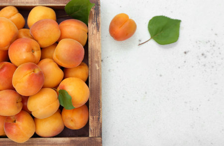 Wooden box with fresh apricots and leaves on white backgroundの写真素材