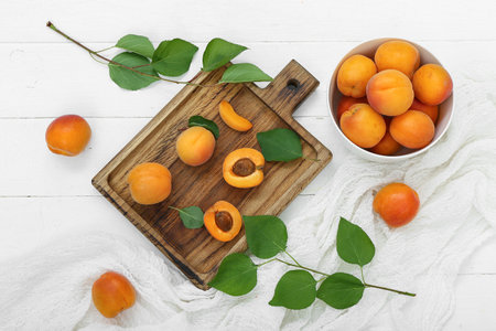 Board and bowl with fresh apricots on white wooden backgroundの写真素材