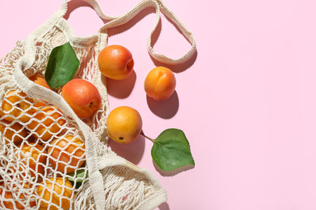 String bag with fresh apricots and leaves on pink backgroundの写真素材