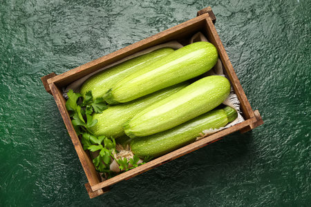 Wooden box with fresh zucchini and parsley on green backgroundの写真素材