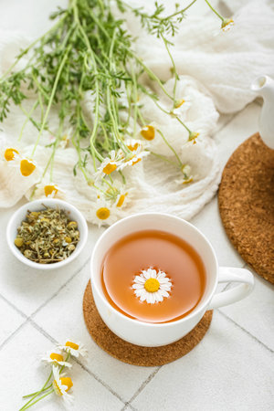 Cup of hot chamomile tea on white tile backgroundの写真素材