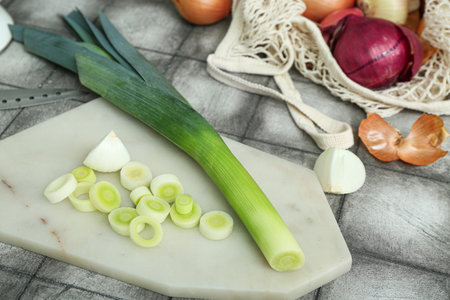 Board and string bag with different kinds of onion on grunge gray backgroundの写真素材