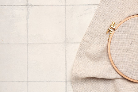 Wooden embroidery hoop with canvas and needle on white tile backgroundの写真素材