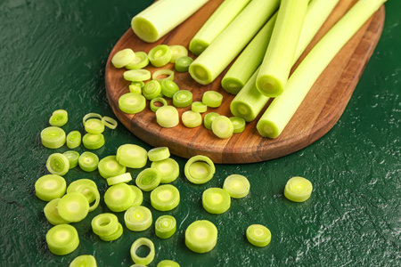 Board with slices of fresh leek on green backgroundの写真素材