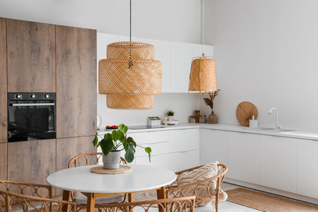 Interior of light kitchen with built-in oven, table, chairs and white counters