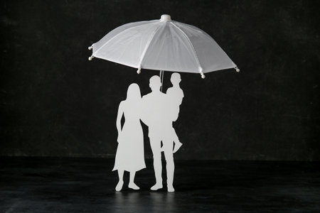 Creative composition with umbrella and paper human figures on black background. health insurance conceptの写真素材