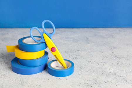 Adhesive tape rolls and stationery scissors on gray tableの写真素材