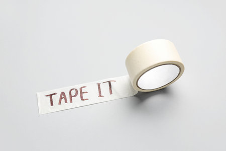 Adhesive tape roll with text TAPE IT on gray background