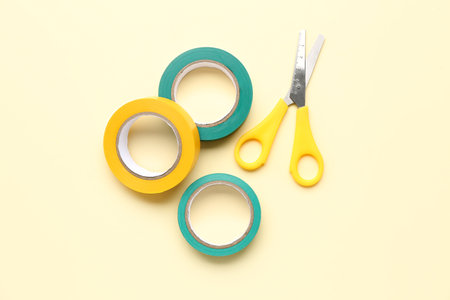 Adhesive tape rolls and stationery scissors on beige backgroundの写真素材