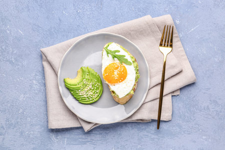 Plate of tasty bruschetta with avocado and egg on gray background