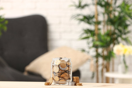 Jar with coins on wooden table against blurred background. Saving conceptの写真素材