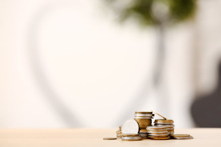 Stacks of coins on wooden table against blurred backgroundの写真素材