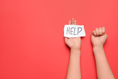 Woman with clenched fist and word HELP on red background. domestic violence conceptの写真素材