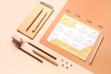 Composition with calendar, notebook, pencils and stationary on beige backgroundの写真素材