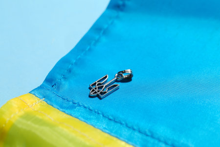 Pendant with Ukrainian coat of arms and flag on blue background, closeup