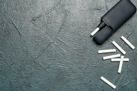 Modern electronic cigar with sticks on dark grunge tableの写真素材