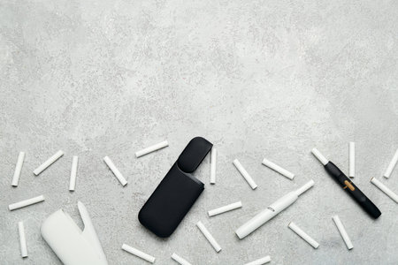 Composition with modern electronic cigars and sticks on gray background