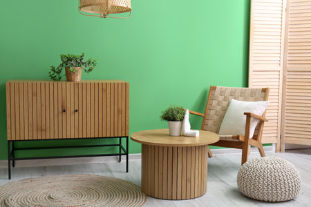 Cozy armchair, coffee table, pouf and wooden cabinet in interior of living roomの写真素材