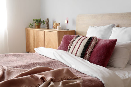 Interior of bedroom with cozy bed and wooden cabinet