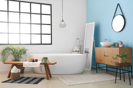 Interior of stylish bathroom with wooden cabinet, bathtub, mirror and sinkの写真素材