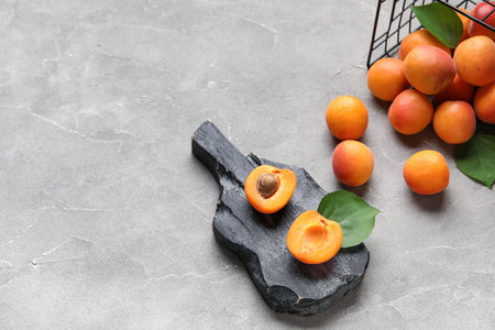 Basket and board with fresh apricots on gray backgroundの写真素材