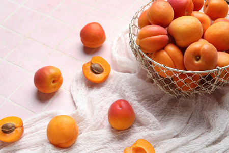 Basket with fresh apricots on pink tile backgroundの写真素材