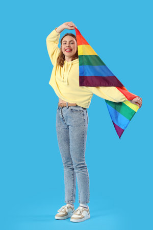Happy young woman with LGBT flag on blue backgroundの写真素材