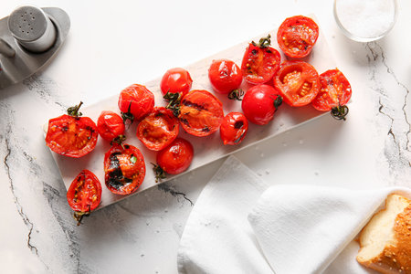Board with tasty grilled tomatoes on white backgroundの写真素材