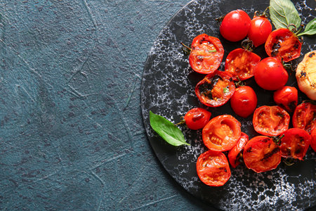 Board with tasty grilled tomatoes and basil on dark backgroundの写真素材